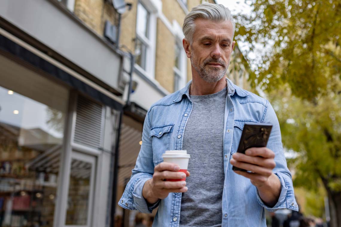 Man outside a coffee shop using a cell phone